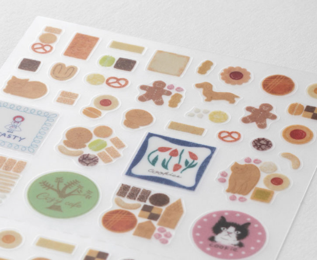 A sheet of cute, pastel-colored sticker designs featuring various baked goods, treats, and illustrations, photographed on a clean white background.