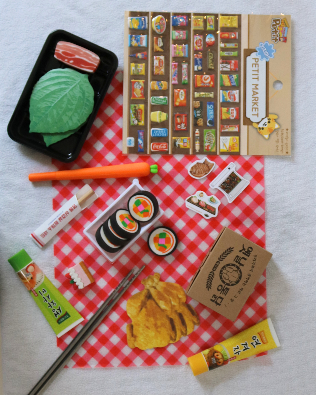 Assorted stationery items including a pen, stickers, and a small bag on a red and white checkered cloth.