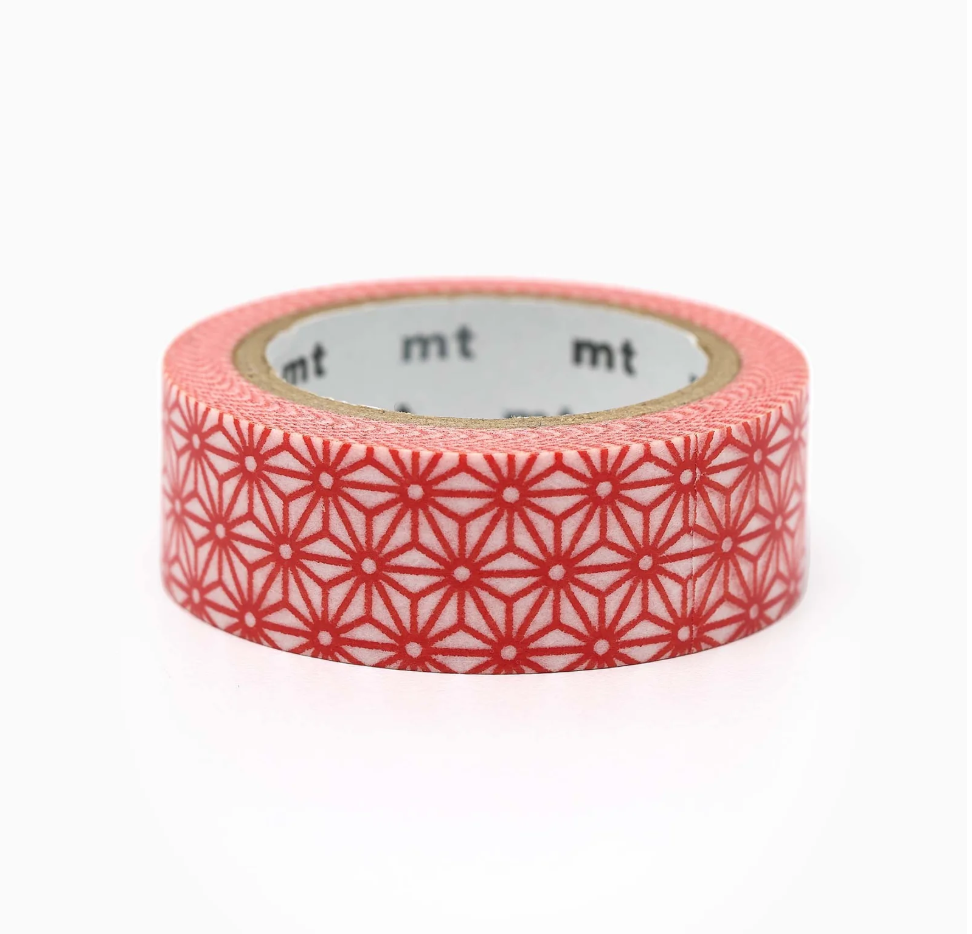 A roll of washi tape with a red geometric star pattern on a light pink base, shown on a clean white background. The brand name 'mt' is partially visible on the inner cardboard core.