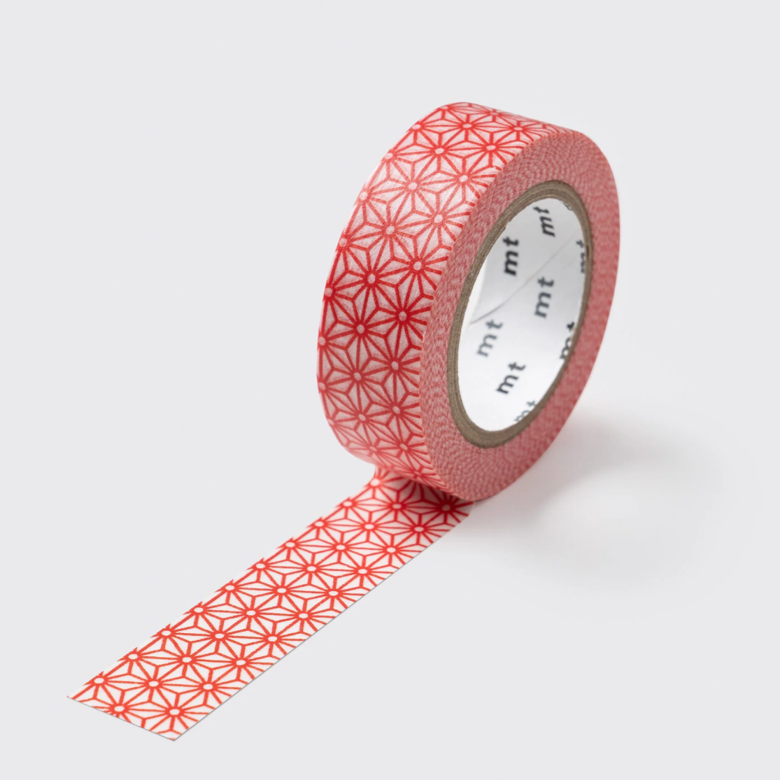 A roll of decorative washi tape with a repeating red geometric starburst pattern on a light pink background, shown with one strip unrolled against a light gray background.