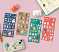 Four colorful Miffy-themed sticker sheets arranged on a pink background, along with a decorated phone case, a white earbud case, a small orange stamp, and part of a planner. The sheets feature cartoon bunnies and cute illustrations in blue, beige, green, and red.