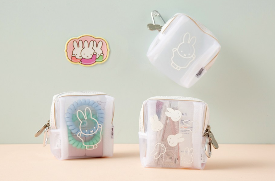 Three small translucent zip pouches with bunny illustrations are arranged on a pastel surface against a pale green background. One pouch is floating upside down, and a matching bunny sticker is shown above.