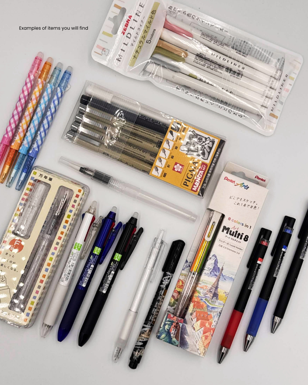 An assortment of stationery pens and pencils arranged on a light gray background, including packaged brands such as Pilot, Uni, and Zebra. The products include ballpoint, gel, and rollerball pens in various colors and tip styles.
