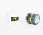 A roll of plaid washi tape with yellow, blue, and green stripes sits next to its white packaging box on a clean white background.
